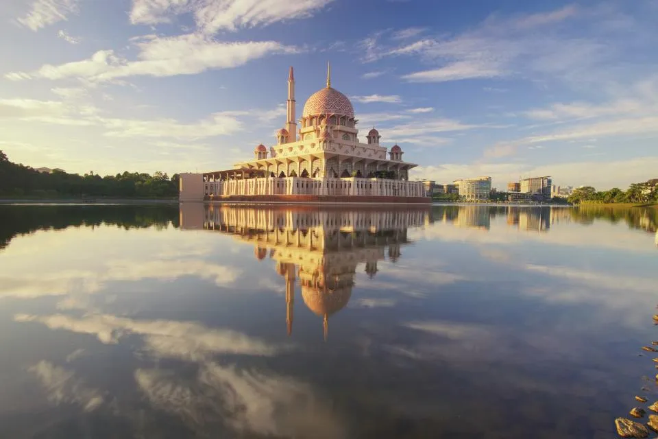 Pink-domed mosque reflected in a still lake in Malaysia