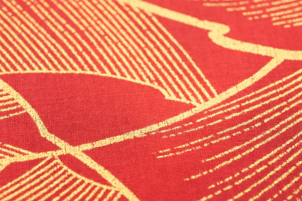 Red cloth with sweeping gold thread motifs in close view